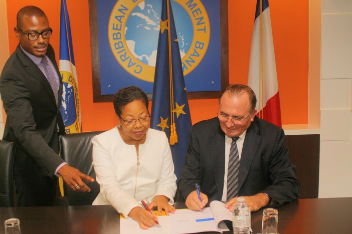 Patricia McKenzie (centre), CDB Vice-President, Operations and Eric de la Moussaye (right), French Ambassador to the Organisation of Eastern Caribbean States and Barbados, sign the Credit Facility Agreement. Looking on is Dave Waithe, Legal Counsel a