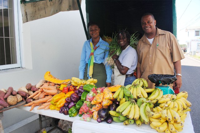 File photo: Mrs Emontine Thompson (centre) at her sales outlet at the Charlestown Public Market, with the PS for Agriculture in the Nevis Island Administration Mr Eric Evelyn and the acting manager for Nevis branch of the Development Bank of St. Kitt