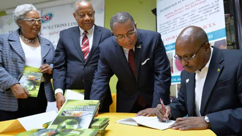 Managing Director of Technological Solutions Limited, Dr. André Gordon (seated), autographs his book - ‘Food Safety and Quality Systems in Developing Countries, Volume 1: Export Challenges and Implementation Strategies for Food Safety&rs