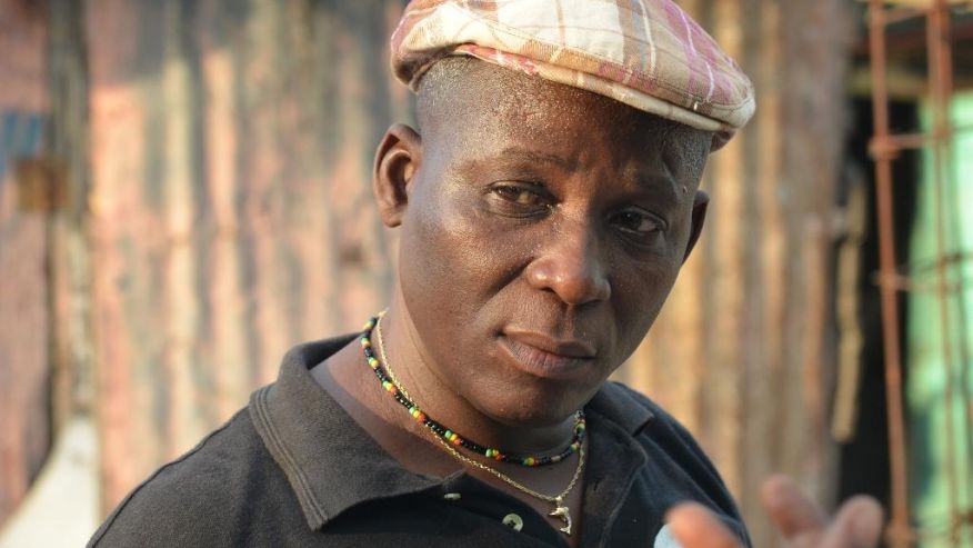 n this April 4, 2016 photo sculptor Andre Eugene speaks to a friend outside his open-air museum and art workshop off a trash-strewn street cutting through some of the poorest neighborhoods in Port-au-Prince, Haiti. He is a founding member of a loose