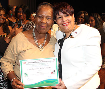 Social Development Minister, Christine Newallo-Hosein, right, presents 73-year-old Marjorie Anderson of the Penal Centre with her certificate during last Friday’s National Poverty Reduction and Eradication Programmes Coordinating Unit graduatio