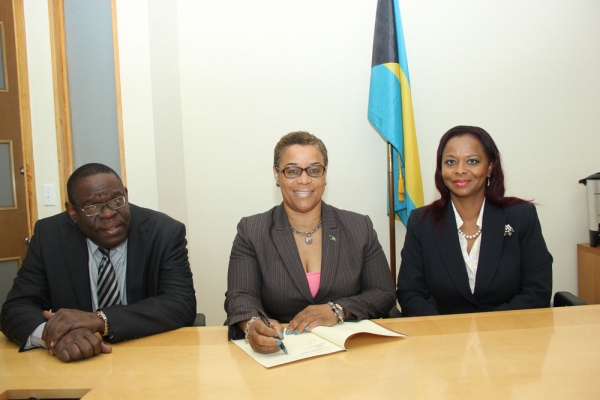 Bahamas Minister of Financial Services, Hon. C. V. Hope Strachan (centre) signing the MOU, while Permanent Secretary, Mr. David Davis and Director of The Bahamas Bureau of Standards and Quality, Dr. Renae Ferguson-Bufford look on.