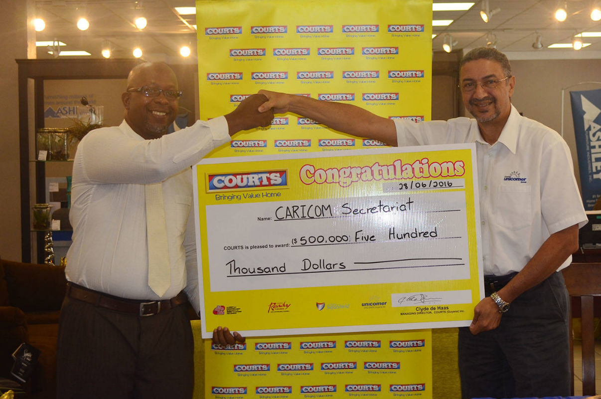Managing Director of Courts, Clyde de Haas, handing over a cheque worth $500,000 to Race and Programme Manager for Crime and Security at CARICOM, Sherwin Toyne-Stephenson