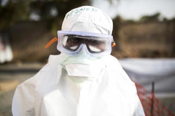 A health worker wearing protective gear stands outside a quarantine zone in a Red Cross facility in the town of Koidu, Kono district in Eastern Sierra Leone December 18, 2014.