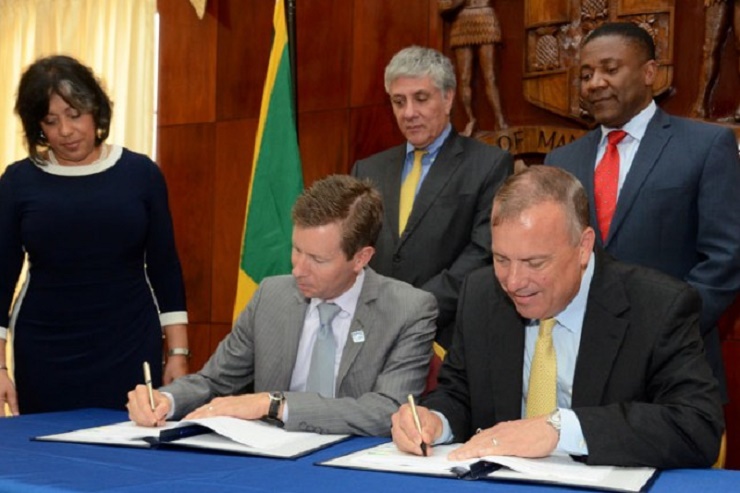 Minister of Science, Technology, Energy and Mining Phillip Paulwell (right-background), looks as Chief Executive Officer of the Overseas Private Investment Corporation (OPIC), John Morton (seated left), and Chairman of WRB Enterprises, G. Robert Blan